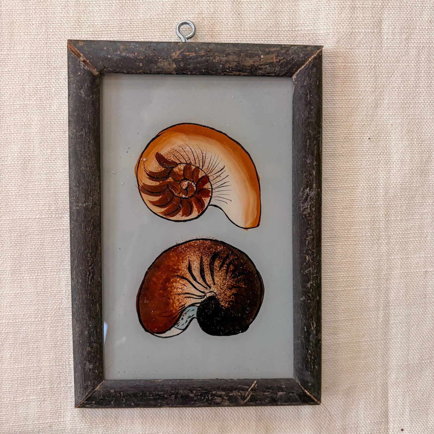 Framed artwork of two stylized nautilus shells on a textured beige background