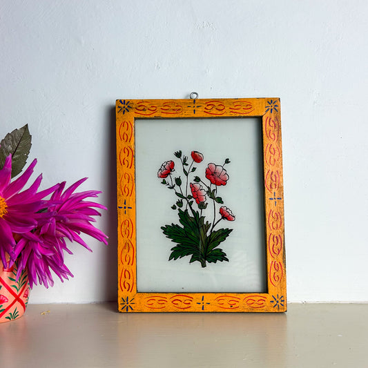 Decorative framed artwork with floral design on a white wall.