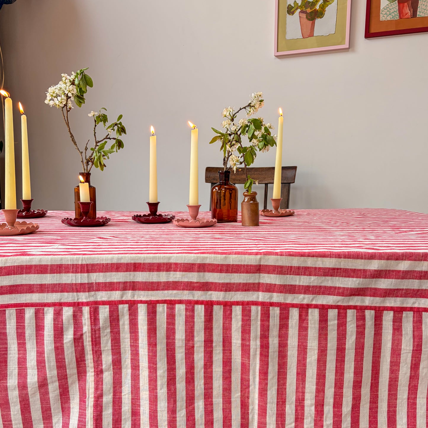 Table setting with candles, flowers, and a striped tablecloth in a room.