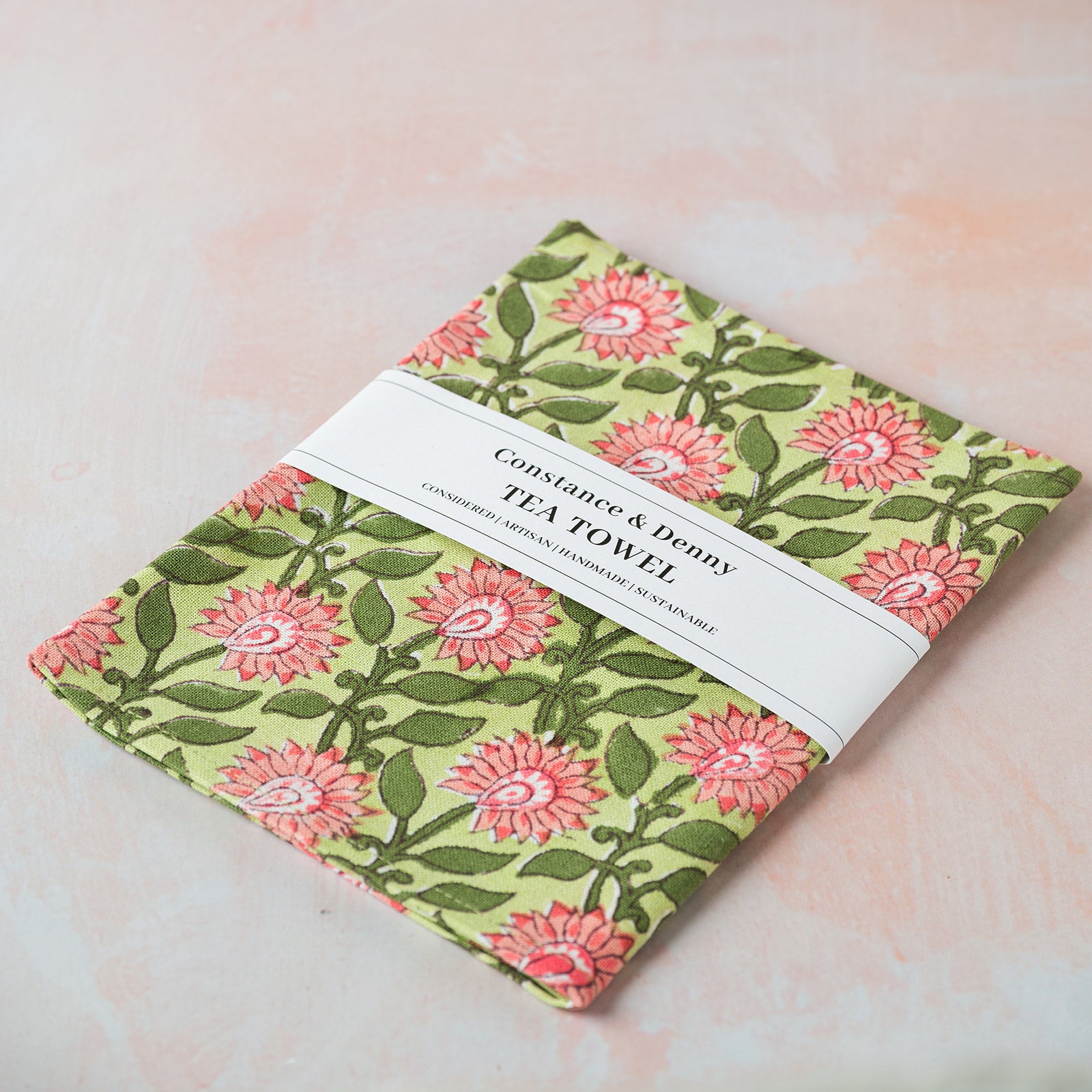 Floral patterned tea towel with a label on a light background