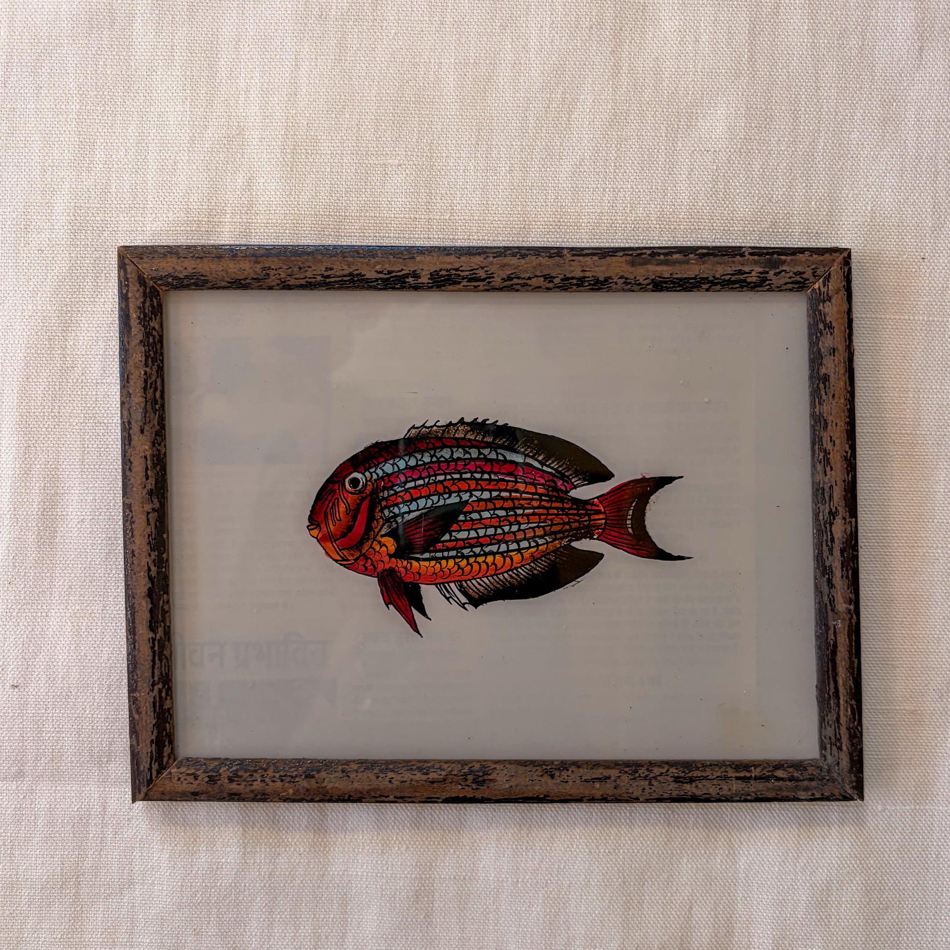 Framed artwork of a colorful fish on a textured beige background