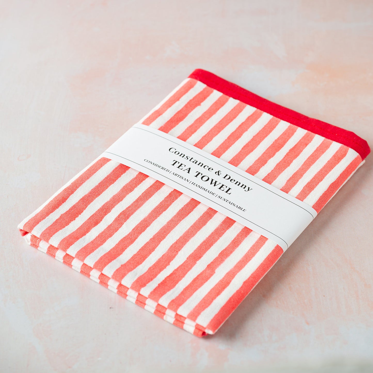 Striped tea towel with red border on a light background