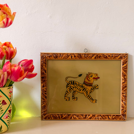 Framed illustration of a tiger on a beige background with flowers to the left.