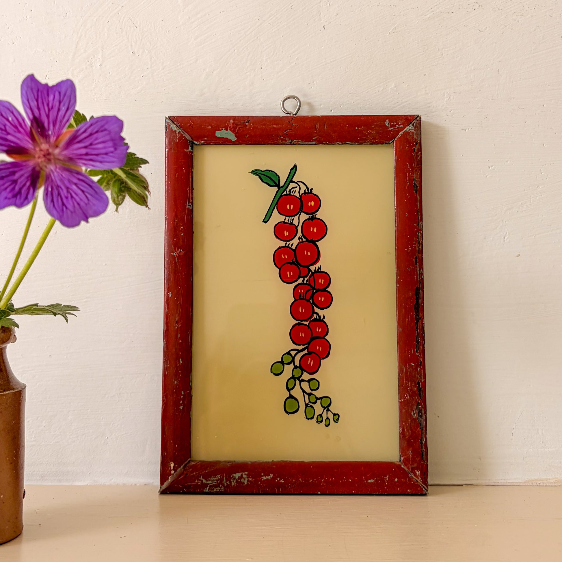 Framed artwork of red berries with a purple flower in the background