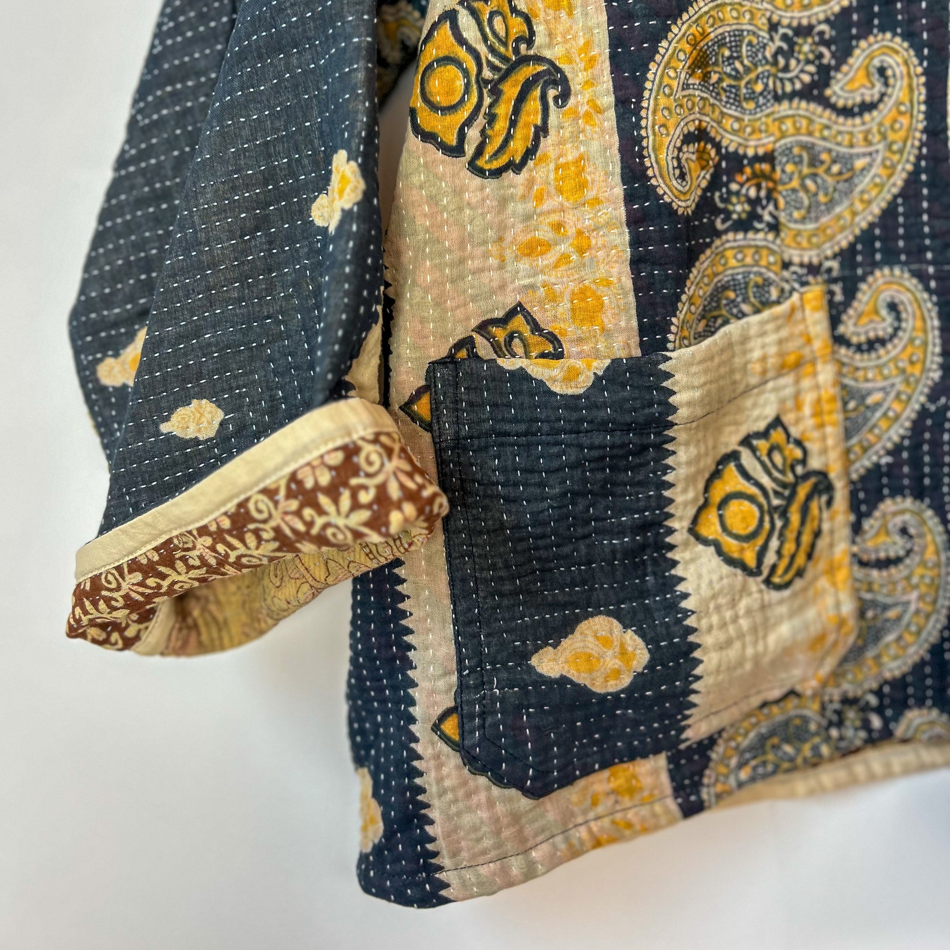Close-up of a traditional quilt with intricate patterns on a white background. Vintage-kantha-jacket-handmade-unique-37-paisley-pattern