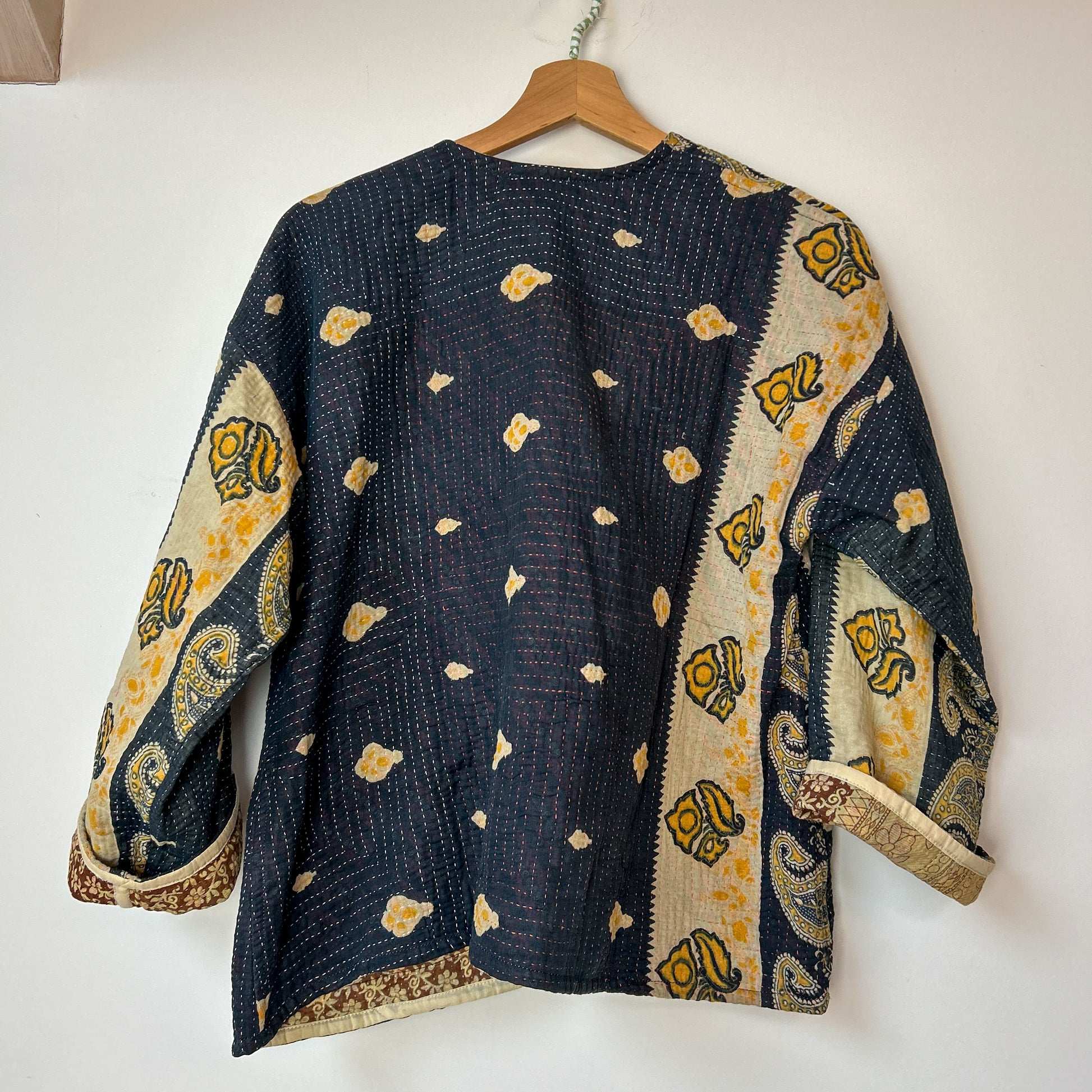 Traditional patterned garment on a hanger against a white background. Vintage-kantha-jacket-handmade-unique-37-paisley-pattern-reverse