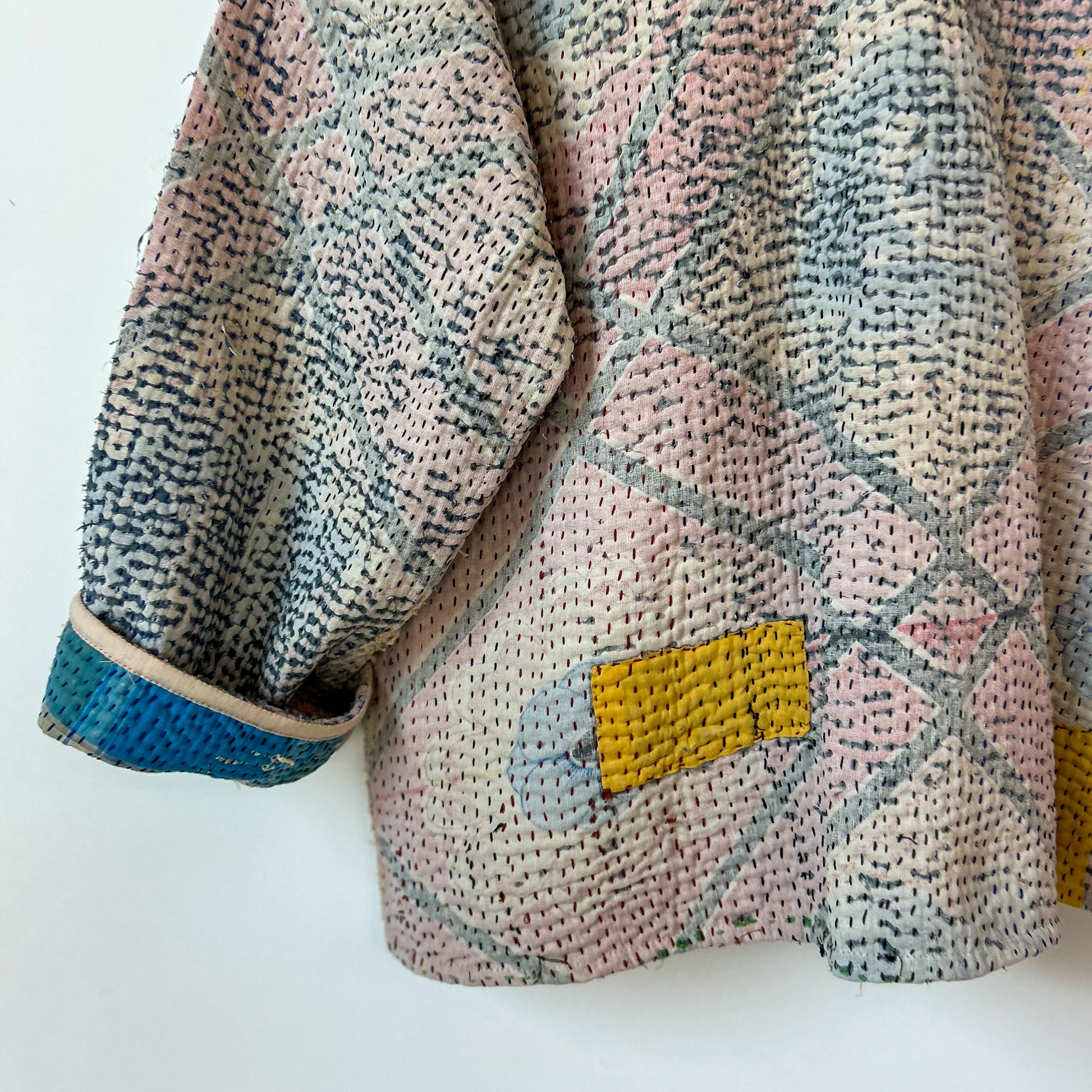 Textured fabric with a diamond pattern and a yellow patch on a white background.Vintage-kantha-jacket-handmade-unique-40-textured-patch