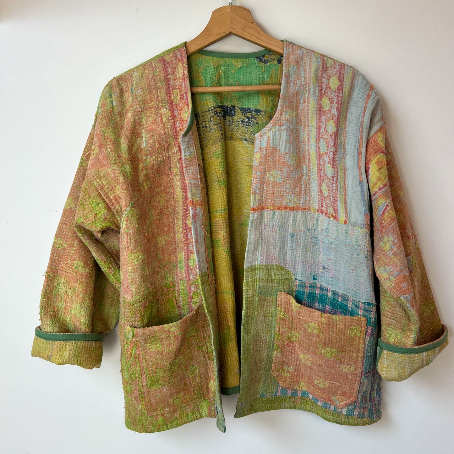 Multicolored textured jacket on a hanger against a white background. Vintage-kantha-jacket-handmade-unique-41-textured