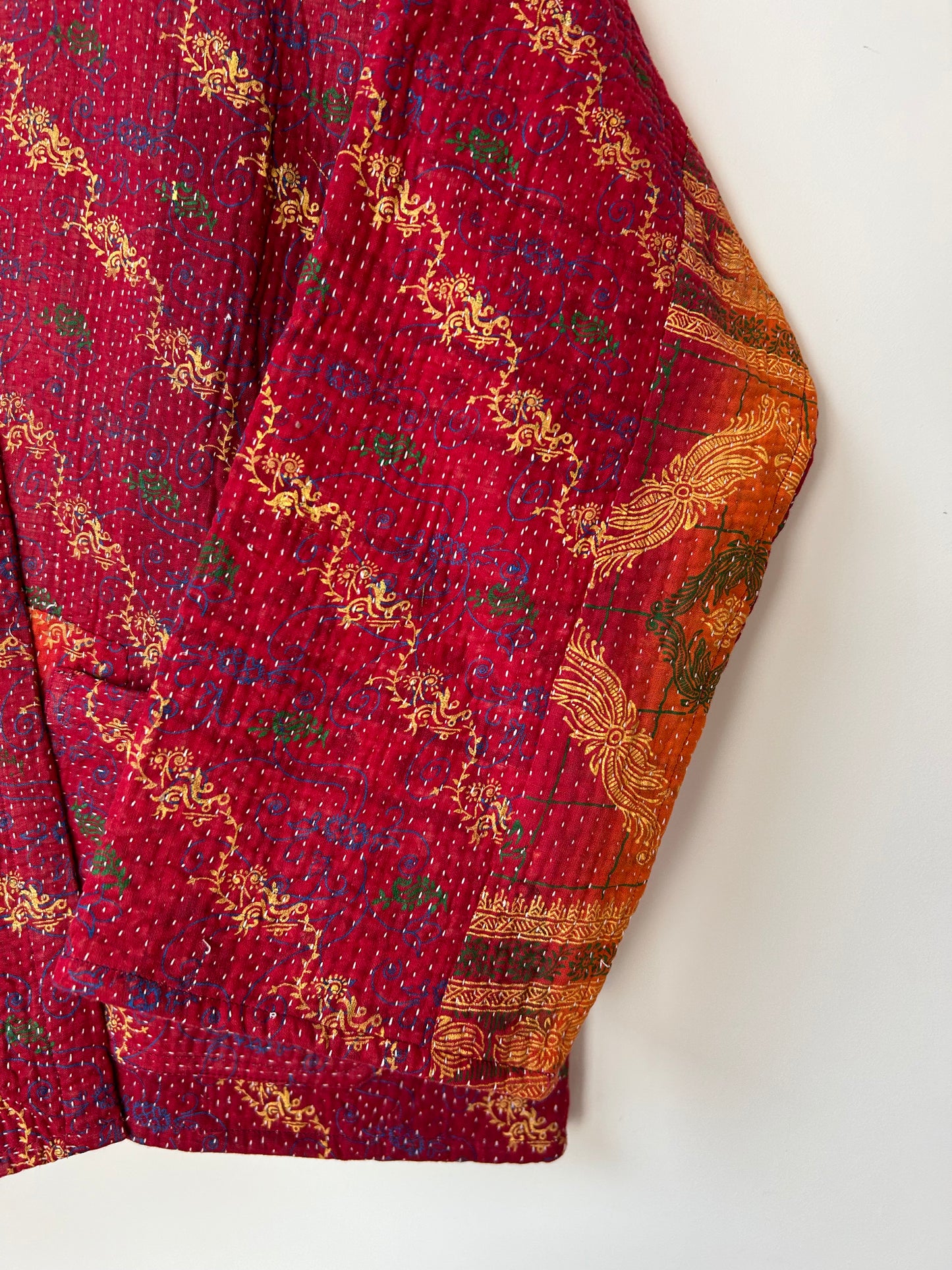 Red fabric with gold and green patterns on a white background. Vintage-kantha-jacket-handmade-unique-43-sleeve