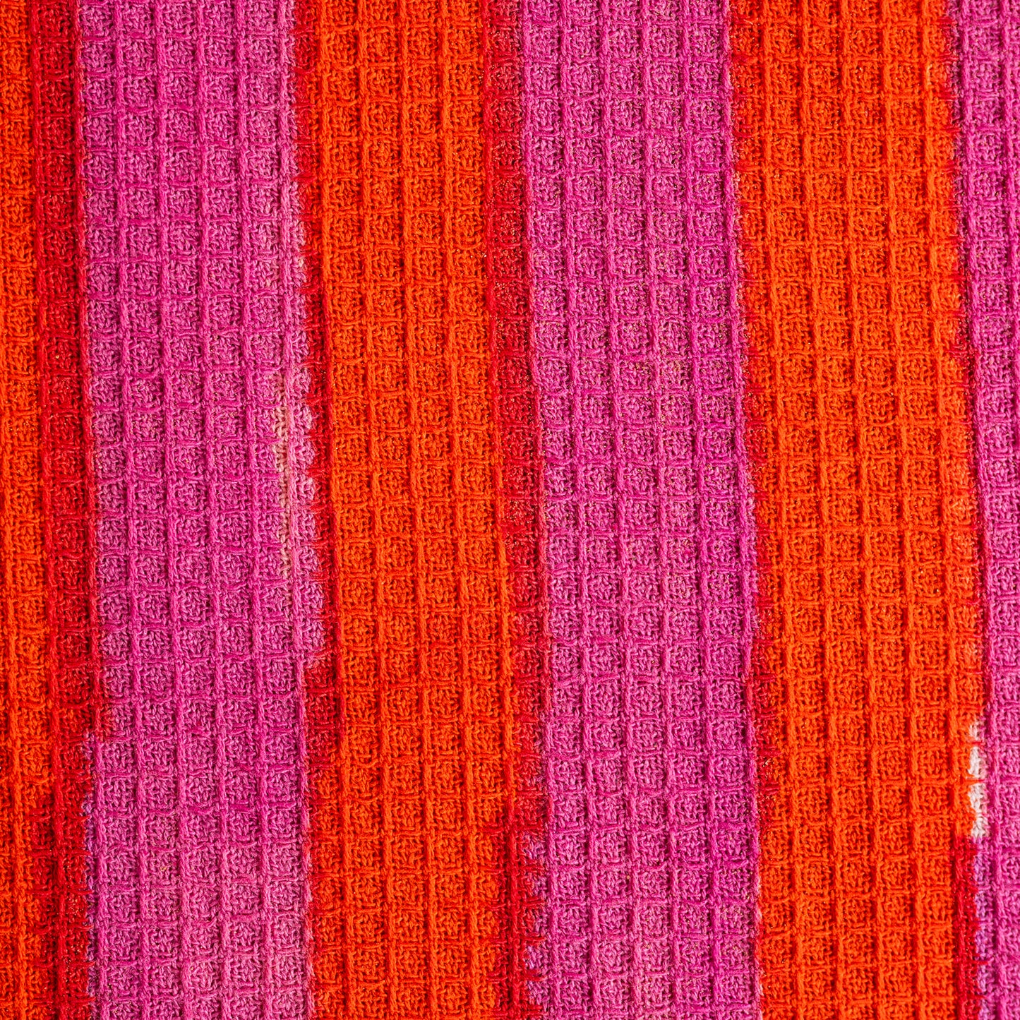 Close-up of textured fabric with alternating pink and orange stripes