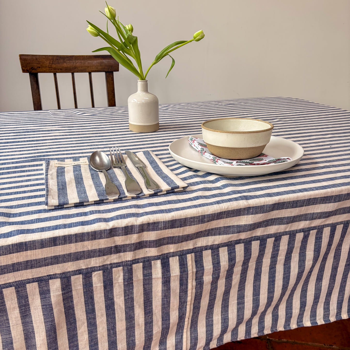 Dining table set with a striped tablecloth, plates, bowls, and cutlery.