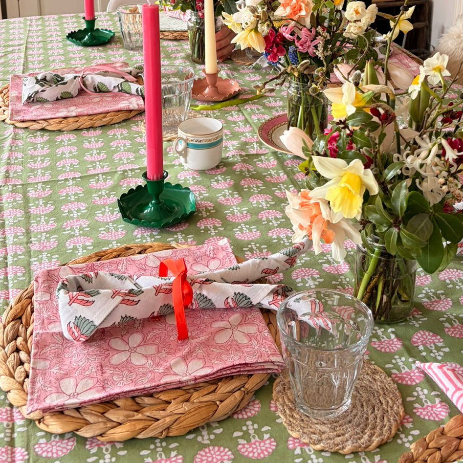 Woman arranging flowers on a decorated dining table with pink candles and floral centerpieces.