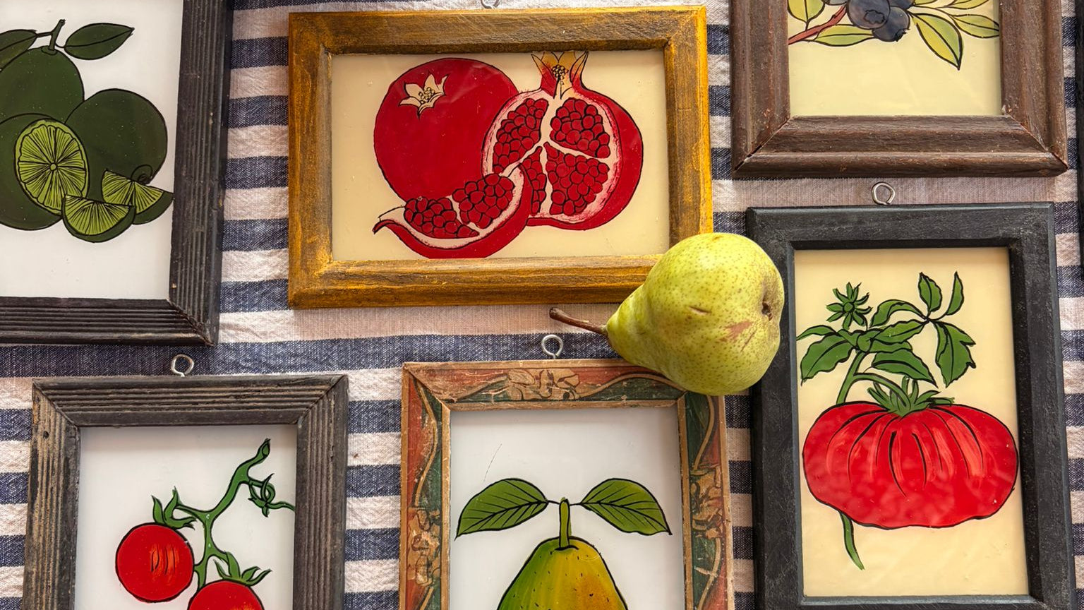 Framed illustrations of fruits and vegetables on a striped background with actual fruits and vegetables.