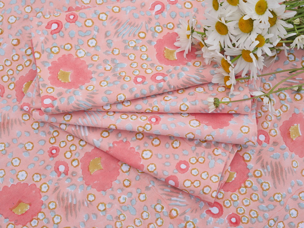 Pink floral napkins with small flowers and a bouquet of daisies on top