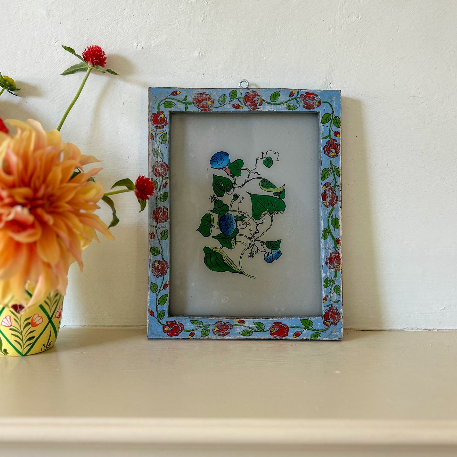 Decorative framed artwork with floral patterns on a white surface with flowers.constance-and-denny-indian-reverse-glass-painting-boxed-packaging-hand-painted-artisan-art-blue-flower