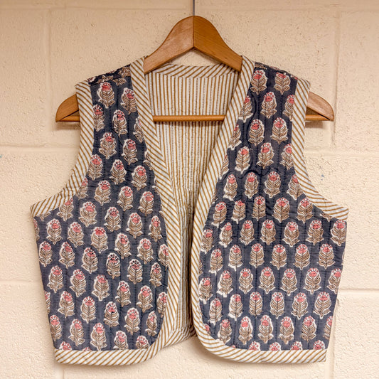 waistcoat hanging on a wooden hanger against a beige wall.