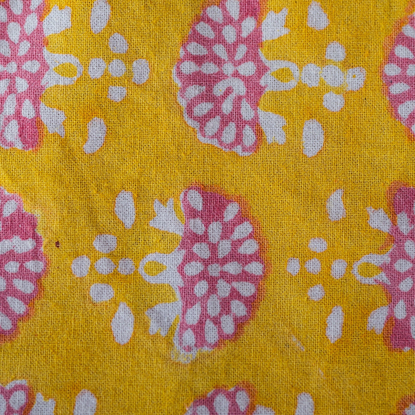 Close-up of fabric with pink and white floral pattern on a yellow background