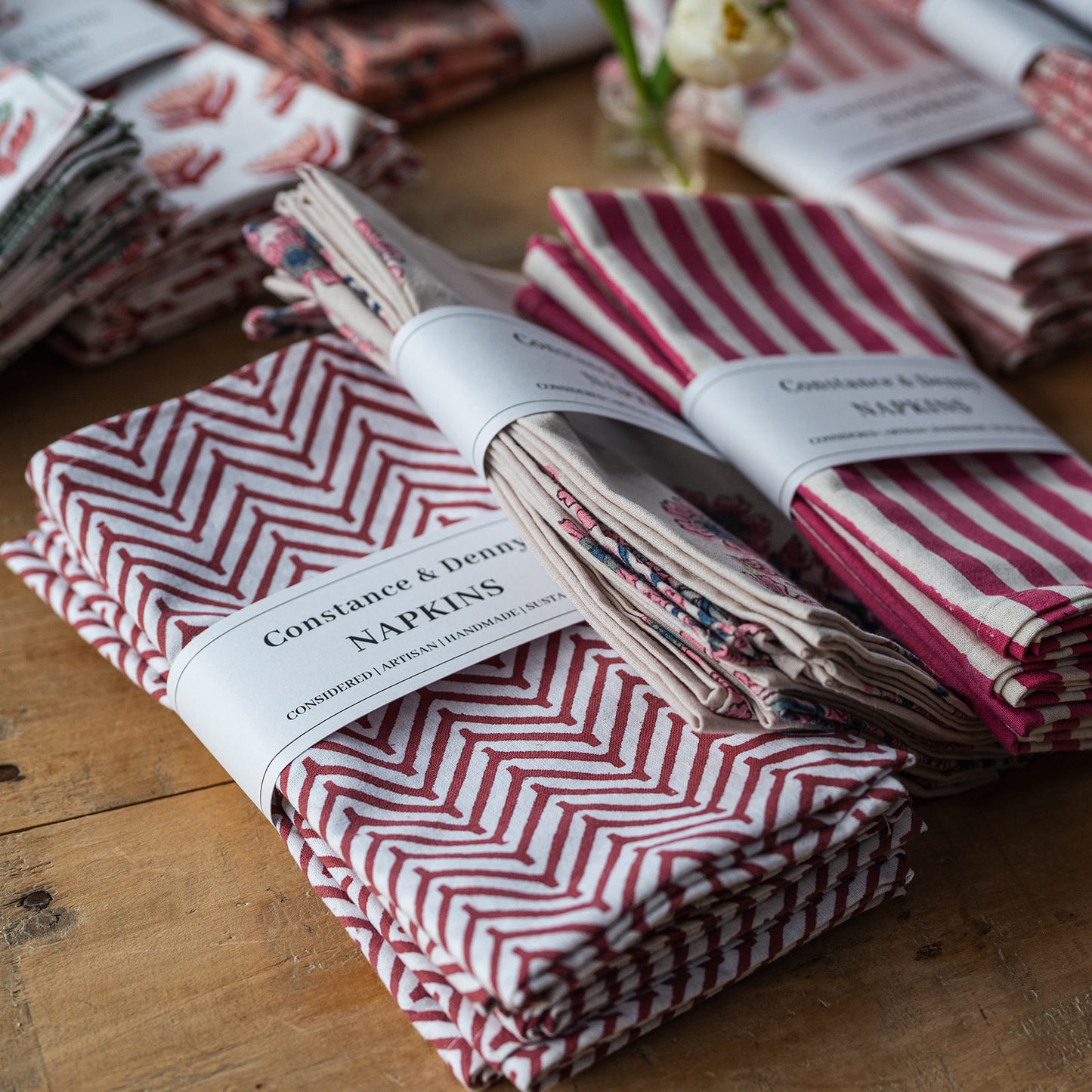 Stacks of red and white patterned napkins with visible branding on a wooden surface.