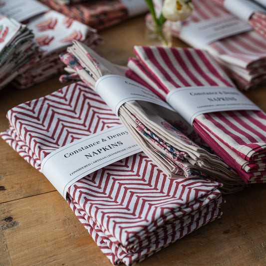 Stacks of red and white patterned napkins with visible branding on a wooden surface.