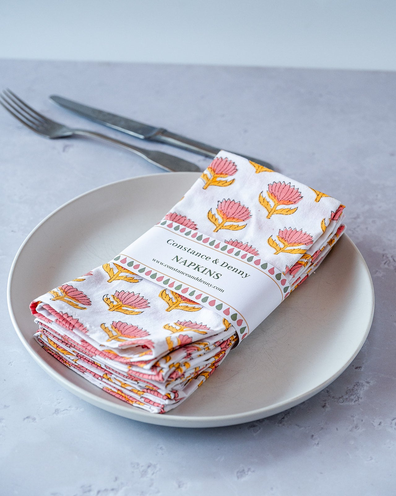 Folded napkins with floral pattern on a plate with cutlery