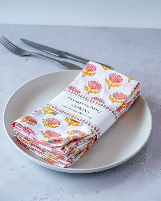 Folded napkins with floral pattern on a plate with cutlery