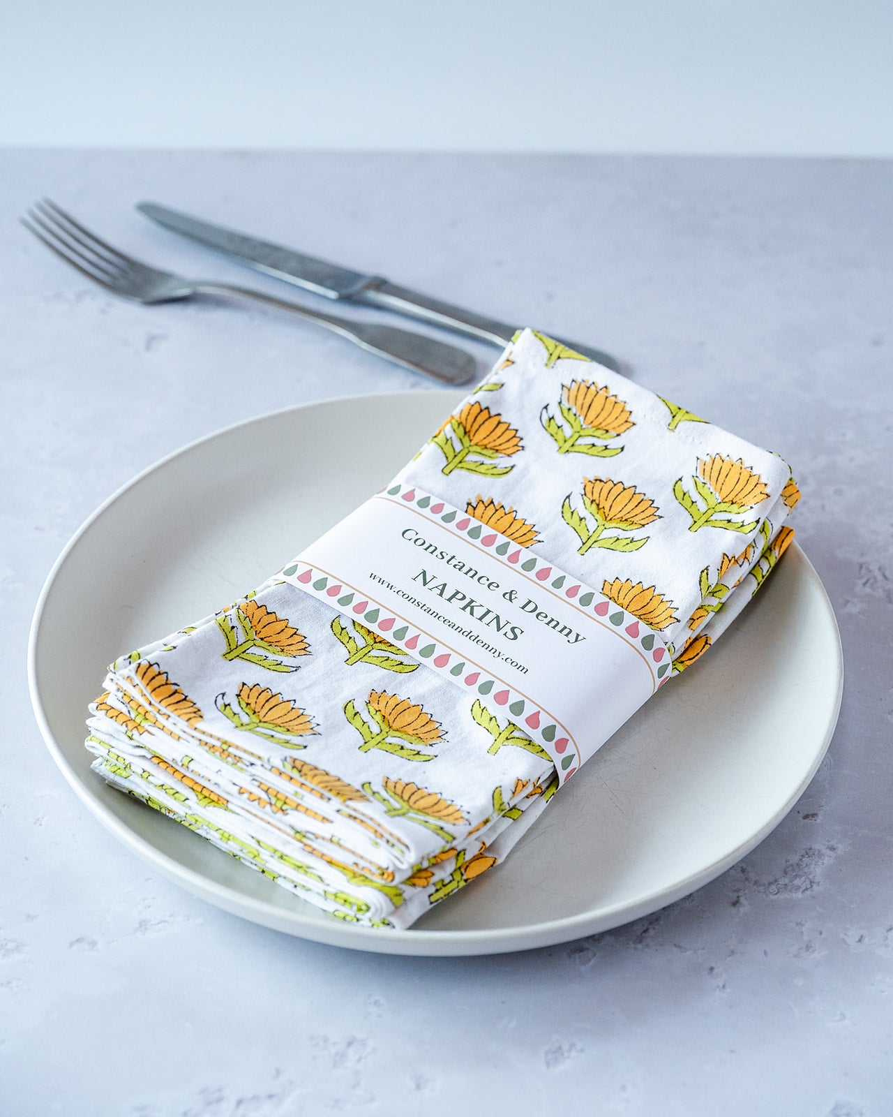 Folded napkins with floral pattern on a plate with cutlery. lotus-flower-napkins-block-printed-sunshine-set
