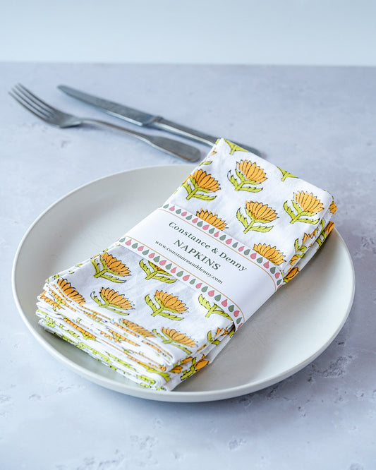 Folded napkins with floral pattern on a plate with cutlery. lotus-flower-napkins-block-printed-sunshine-set