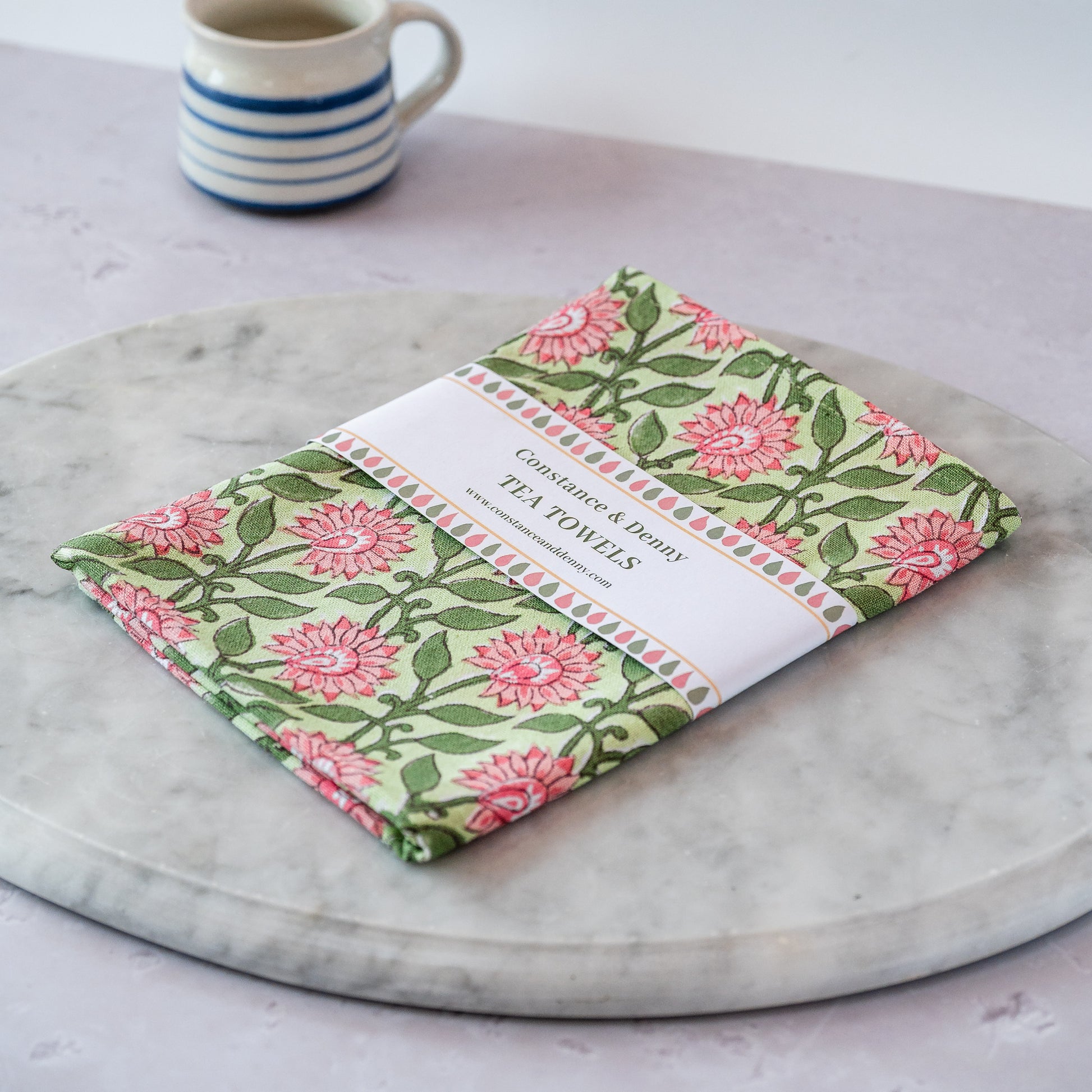 Floral tea towel on a marble surface with a cup in the background