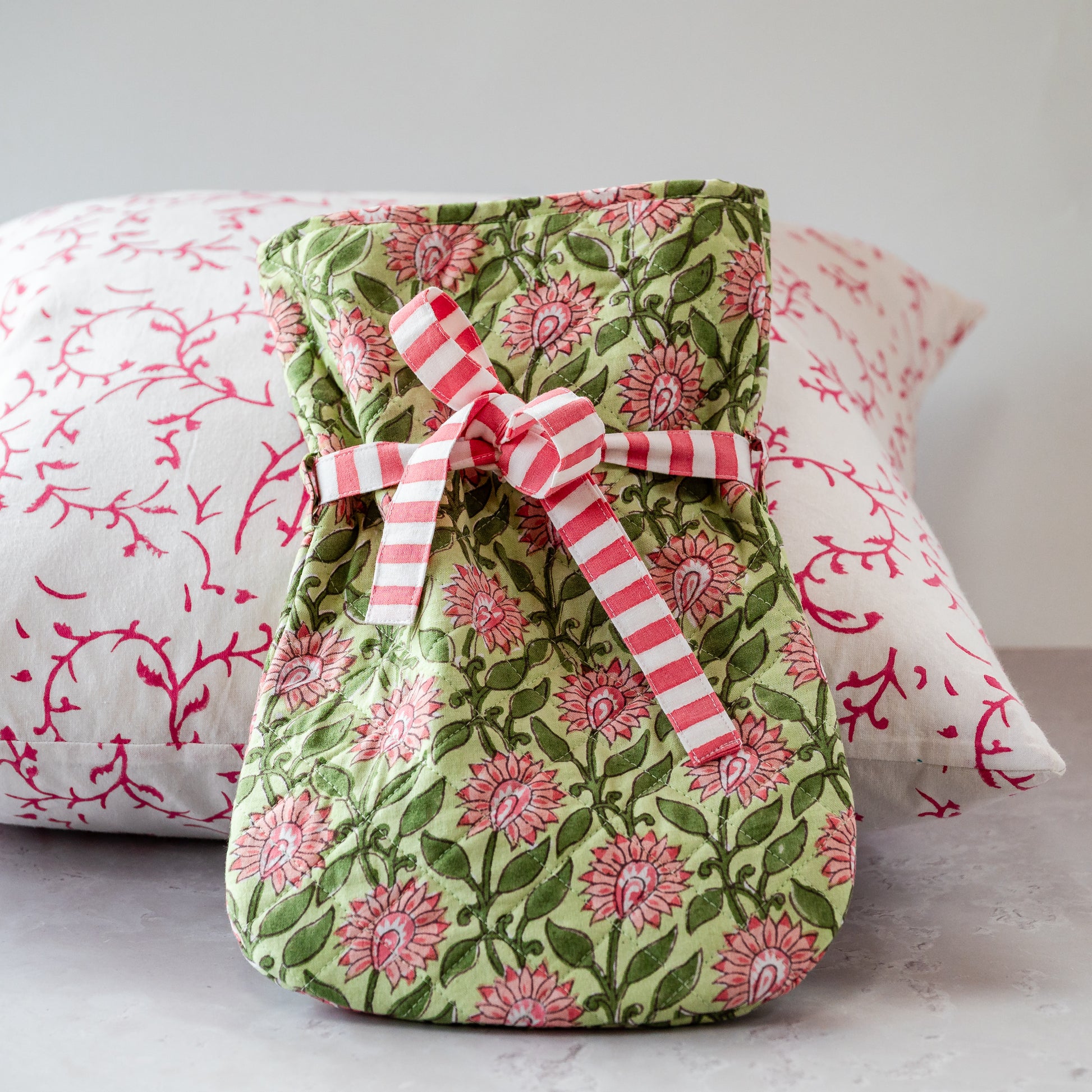 Fabric dHOT WATER BOTTLE with floral pattern and red and white ribbon on a light background
