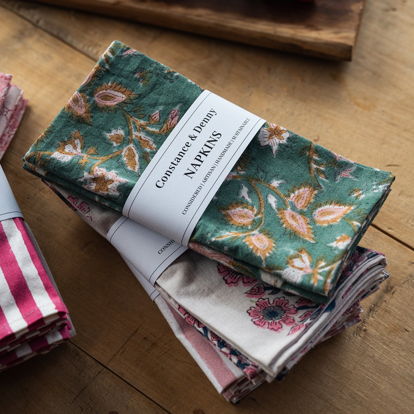 Set of floral patterned napkins with a visible brand label on a wooden surface