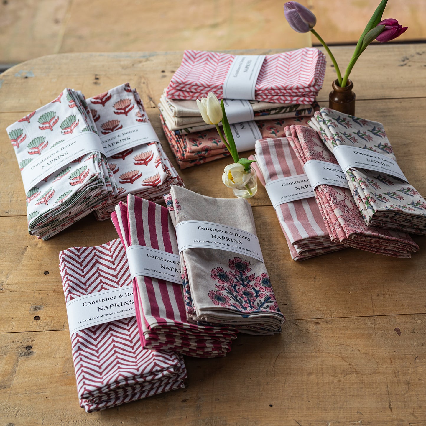Set of folded napkins with floral and striped patterns on a wooden surface.