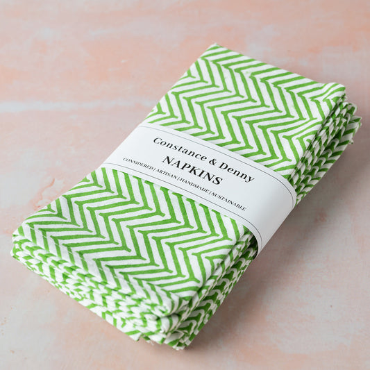 Pack of green and white chevron patterned napkins with a label on a light pink background