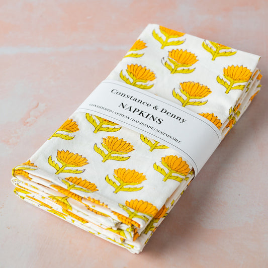 Folded napkins with yellow floral pattern on a light pink background