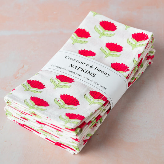 Stack of floral-patterned napkins with 'Constance & Denny' label on a light background