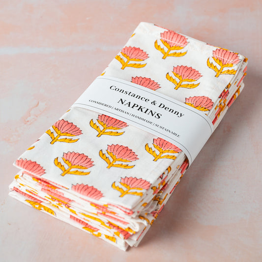 Pack of Constance & Denny napkins with floral design on a light pink background