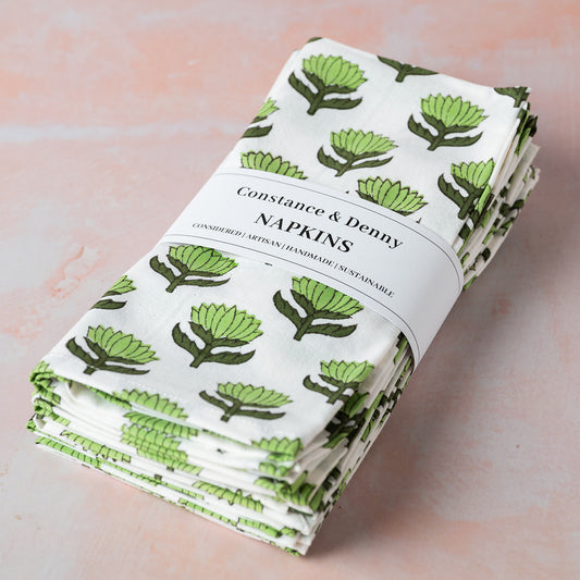 Folded napkins with green leaf pattern on a white label, on a light pink background