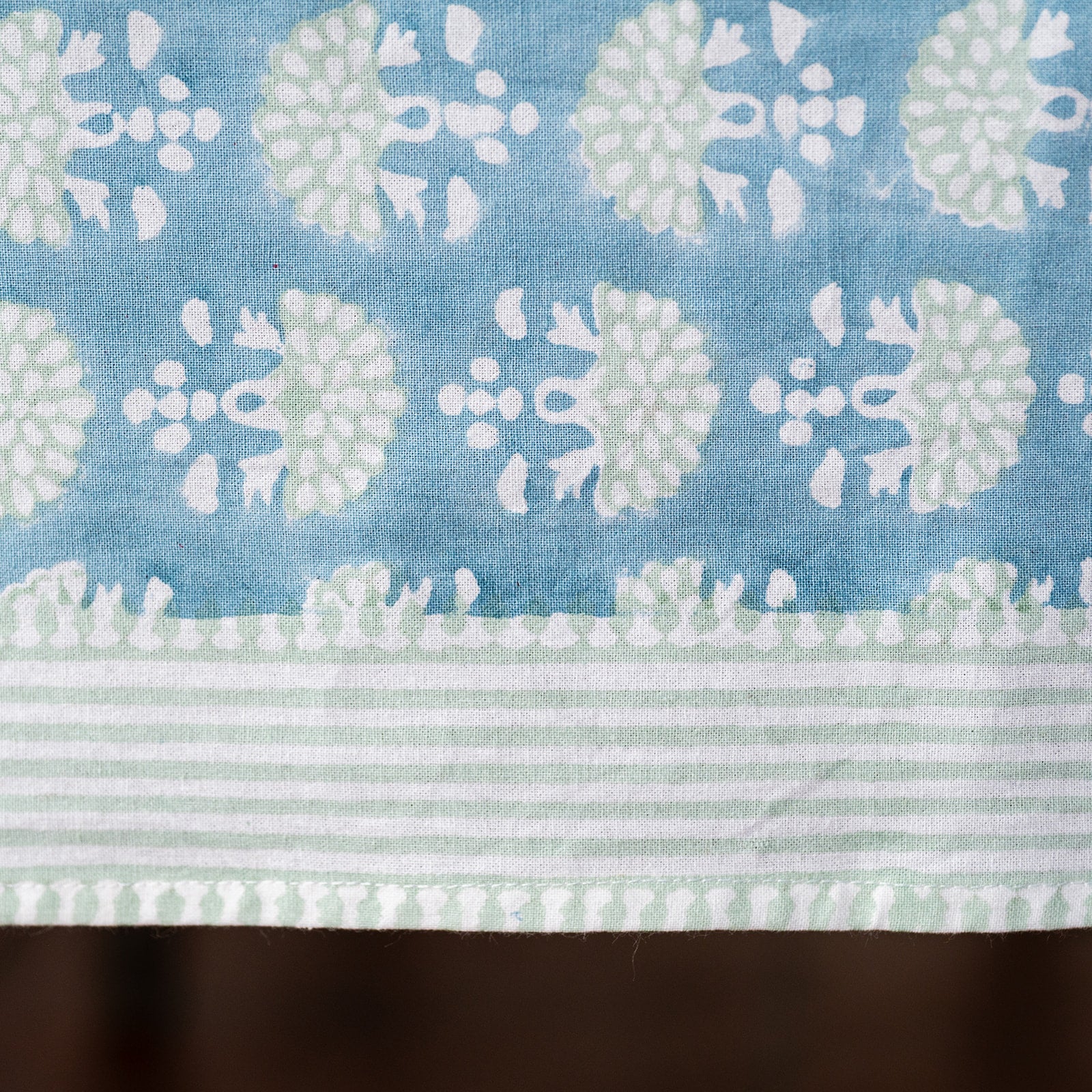 Fabric with a pattern of white and light green flowers on a blue background
