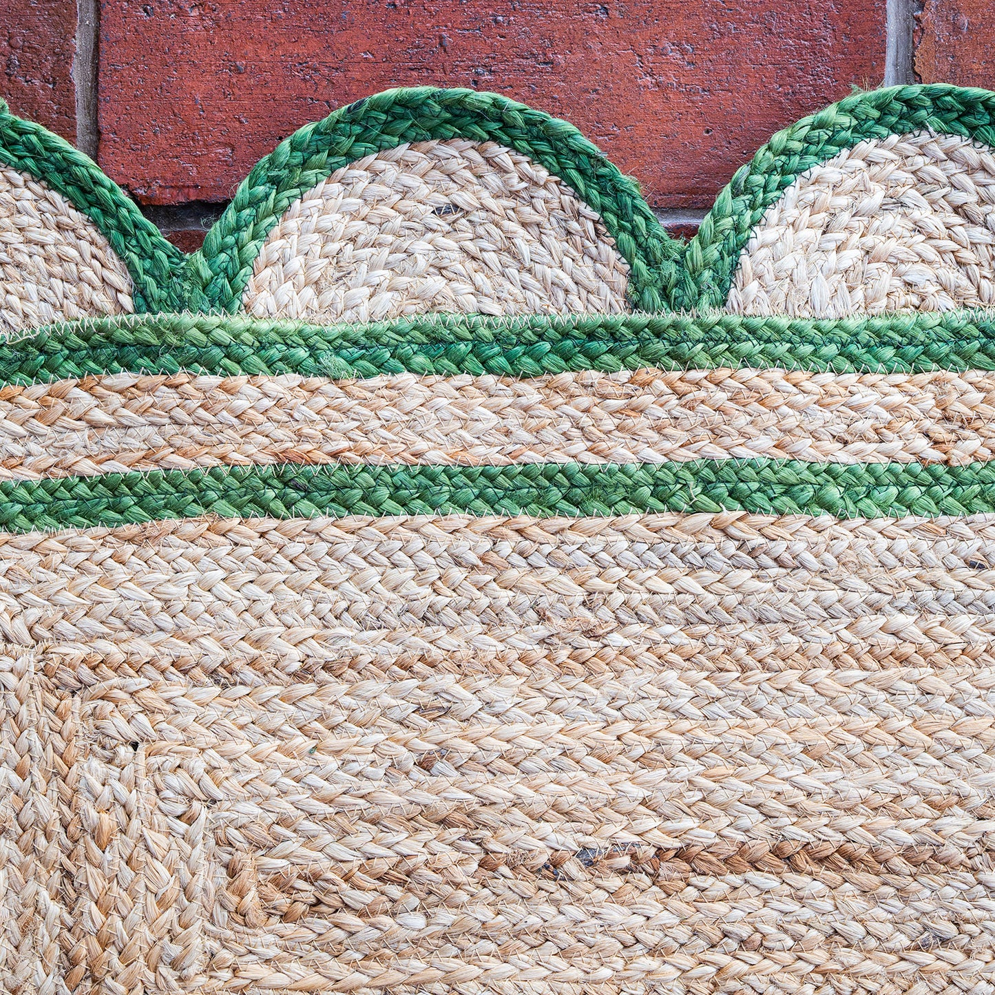 Close-up of a woven mat with green and beige pattern against a wooden background