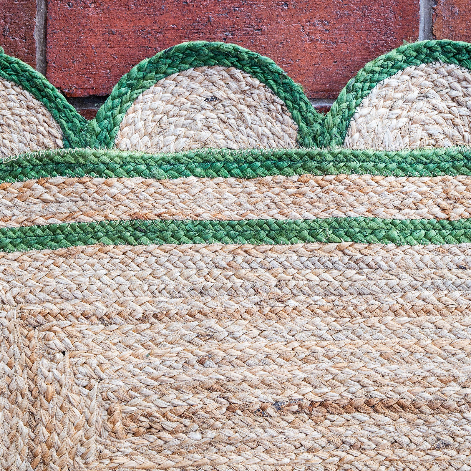 Close-up of a woven mat with green and beige pattern against a wooden background