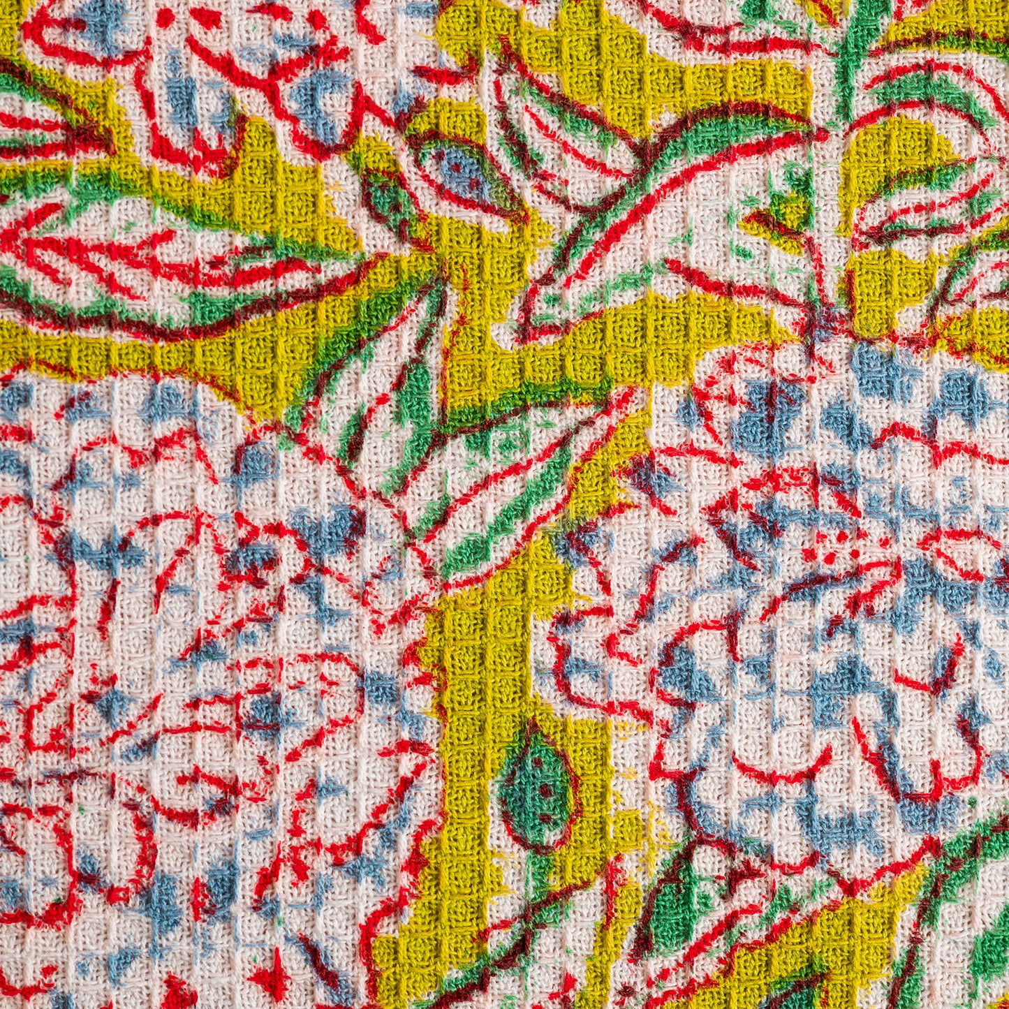 Close-up of a colorful floral patterned fabric with red, blue, green, and yellow colors.