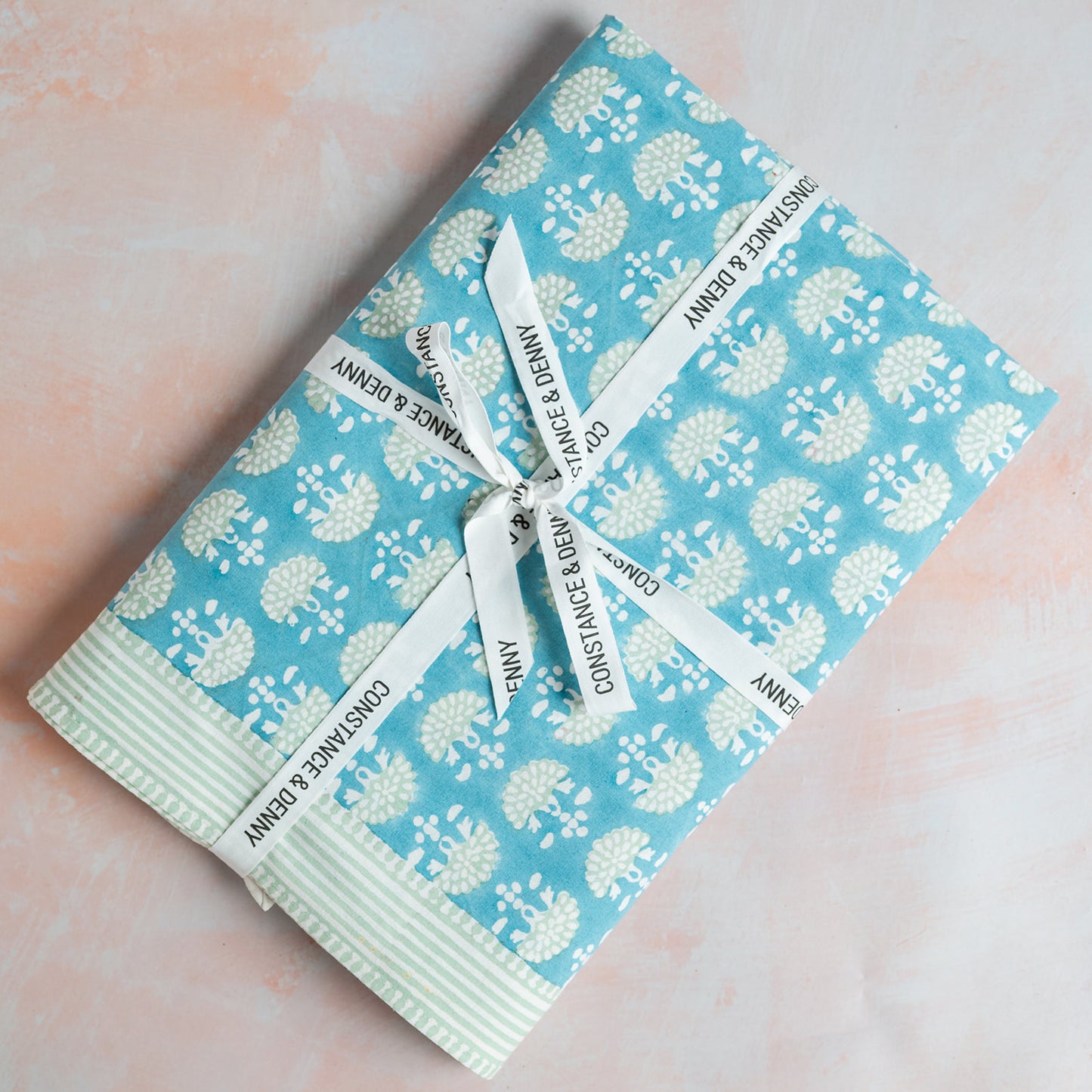 Packaged product with floral pattern and white ribbons on a soft pink background