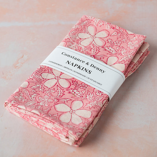 Pack of pink floral napkins with 'Constance & Denny' label on a light pink background