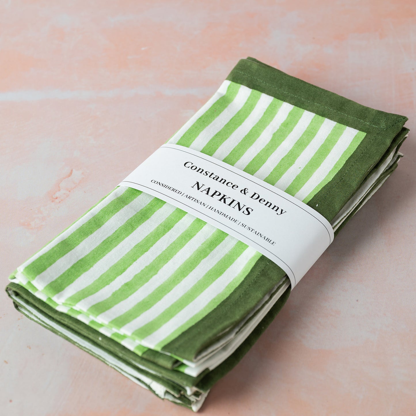 Folded green and white striped napkins with a label on a light pink background
