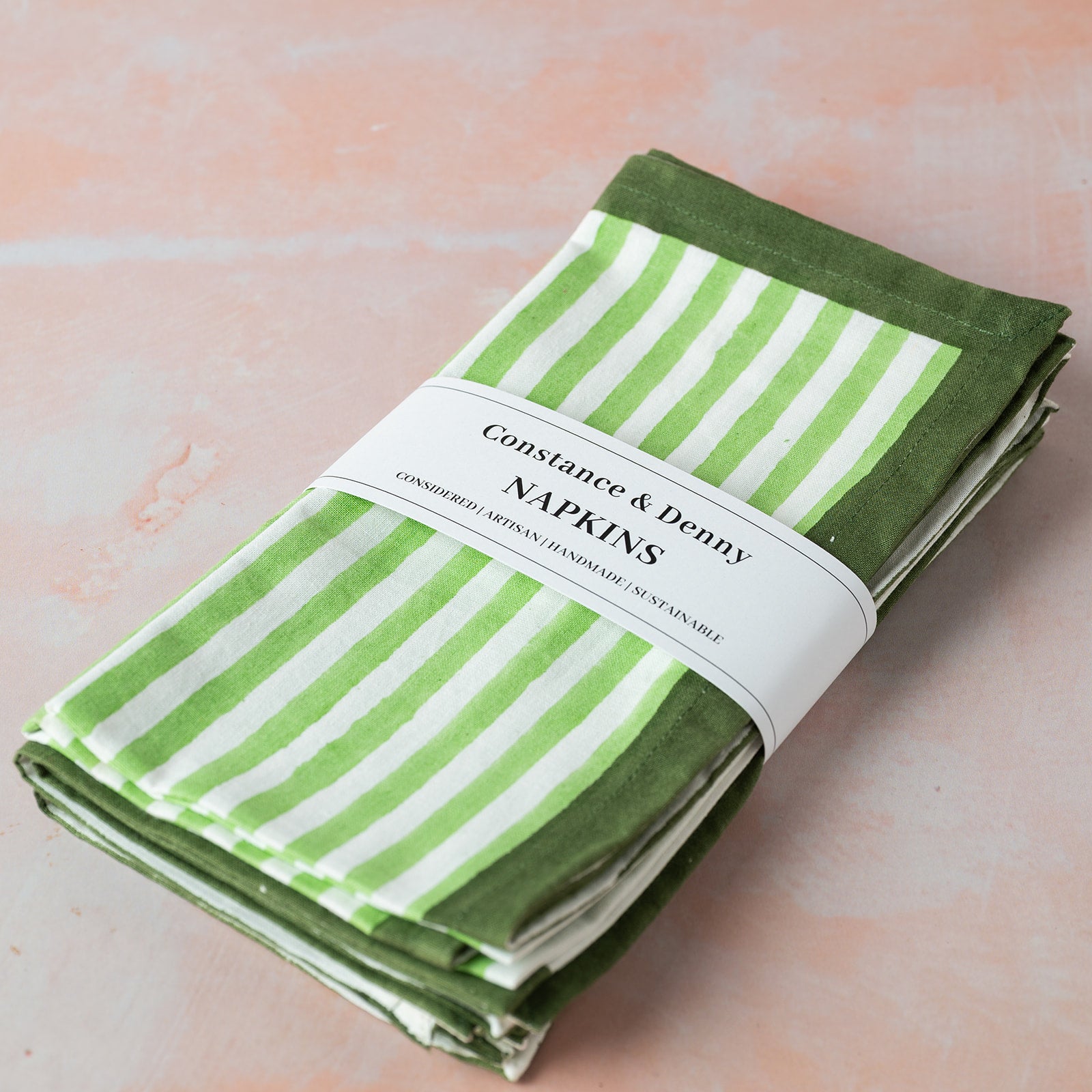 Folded green and white striped napkins with a label on a light pink background