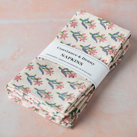 Pack of floral-patterned napkins with a visible brand label on a light pink background.