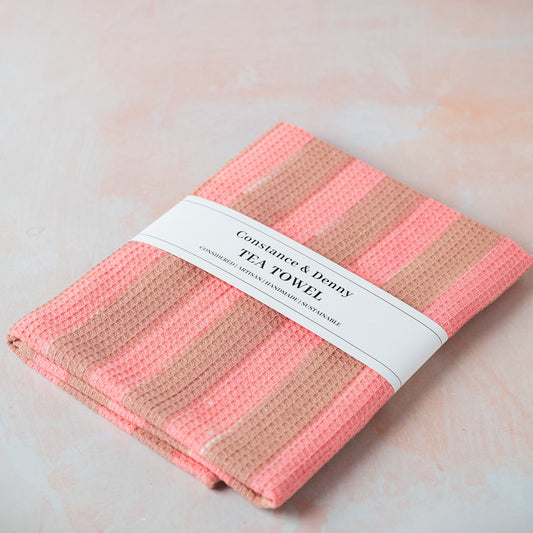 Folded pink and beige tea towel with a label on a light background