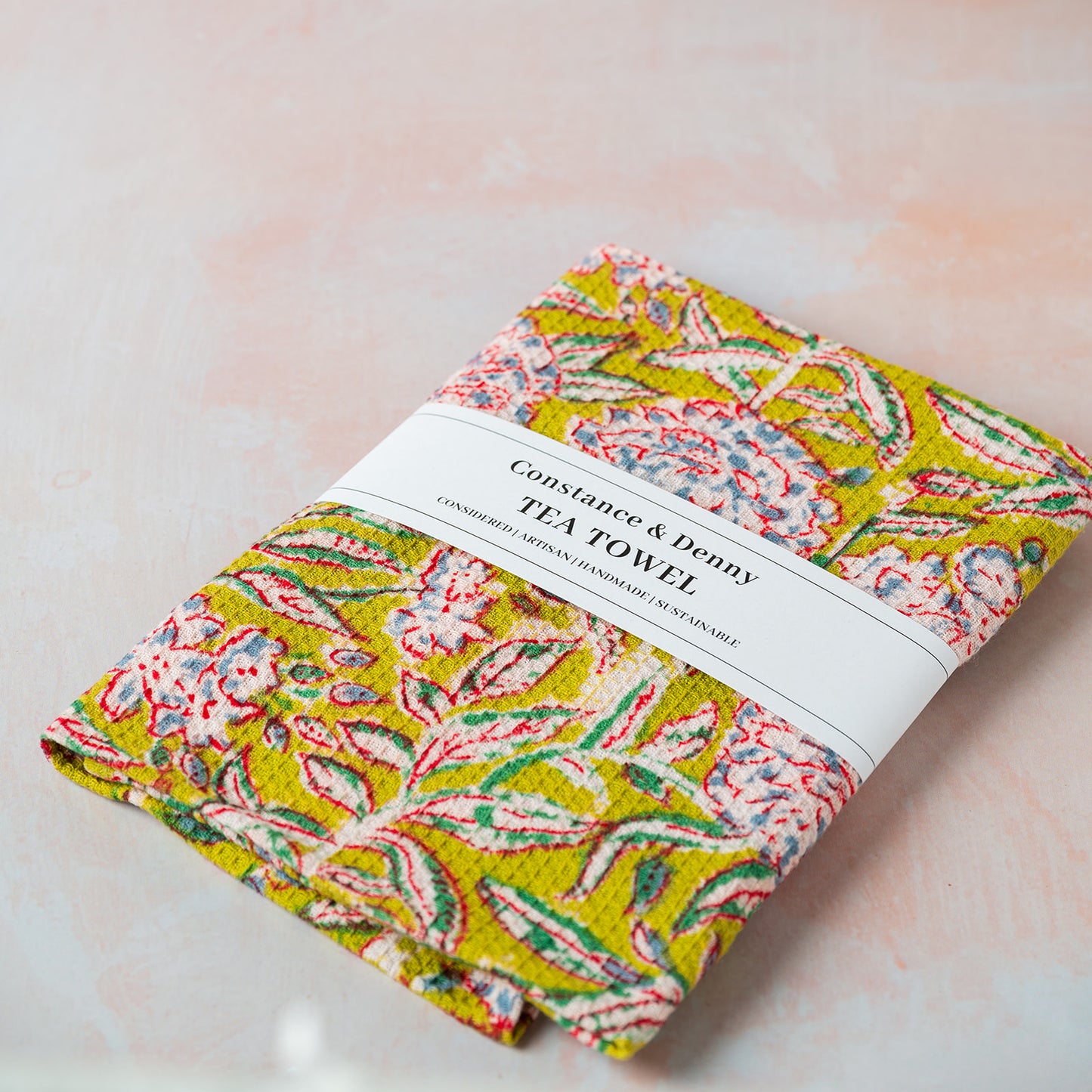 Folded floral tea towel with a label on a light background