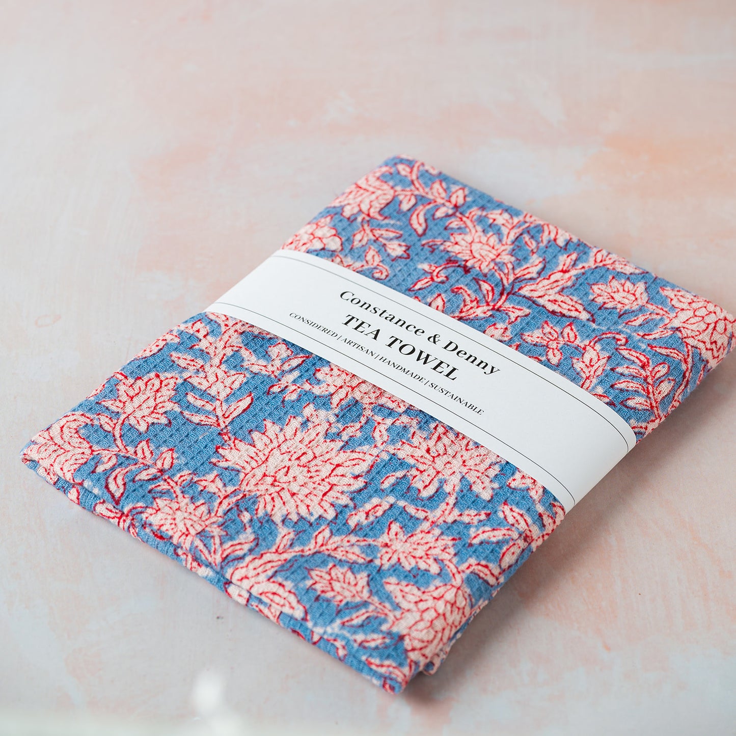 Folded floral tea towel with a label on a light background