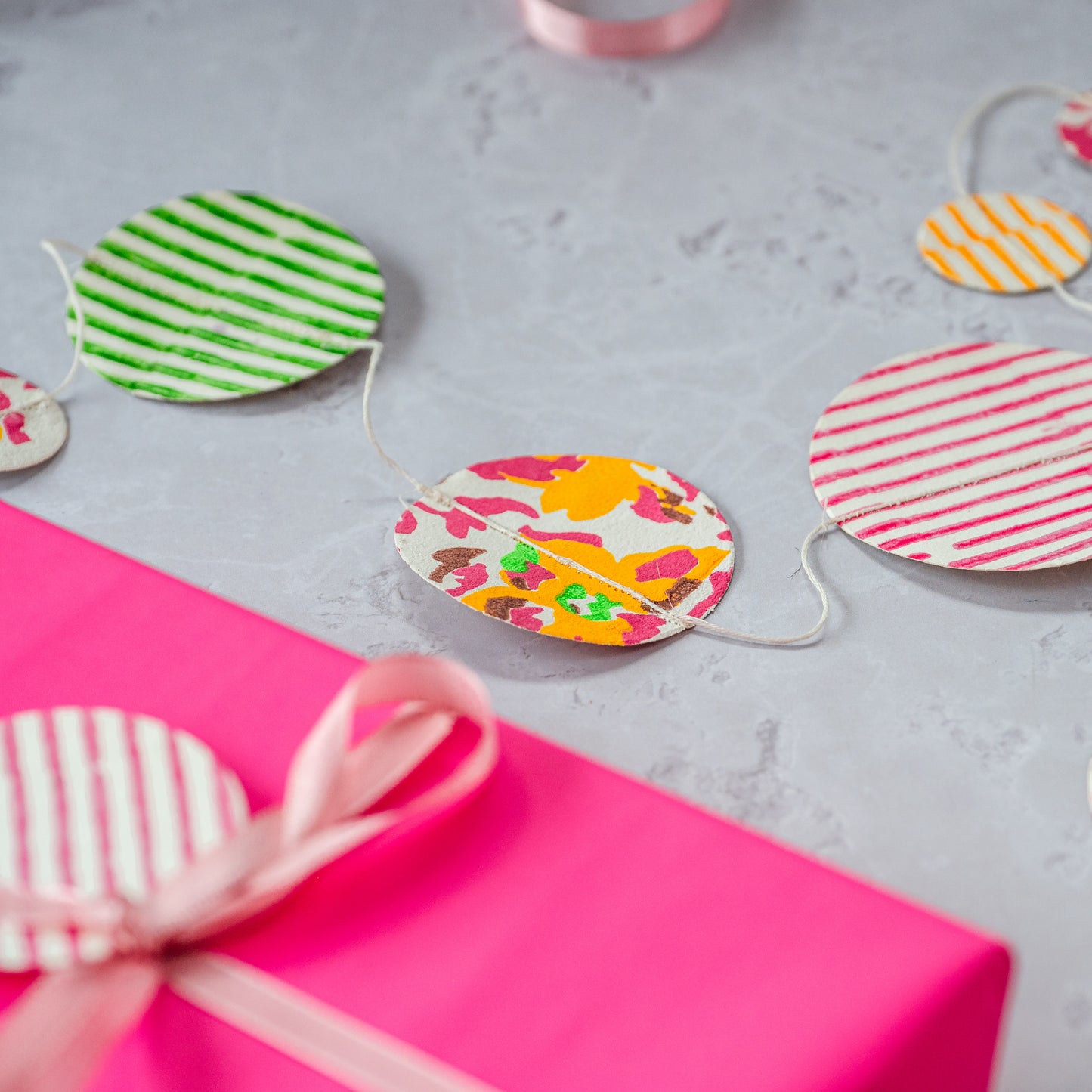 Colorful paper circle garland on a pink surface with a gray background