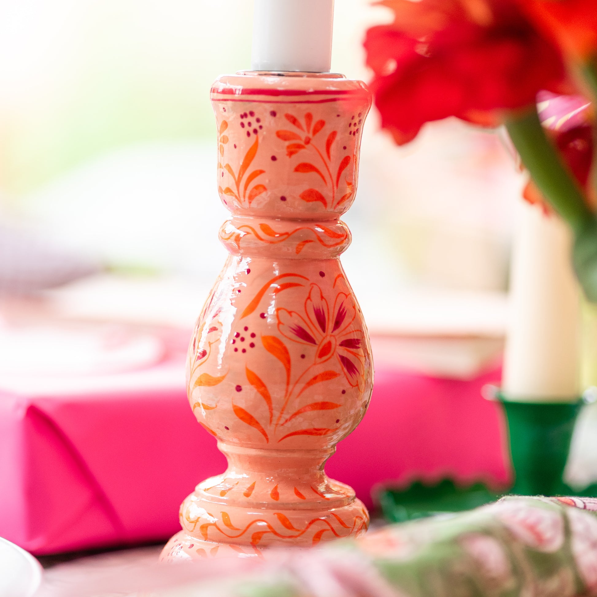 Decorative pink candle holder with floral patterns on a blurred background
